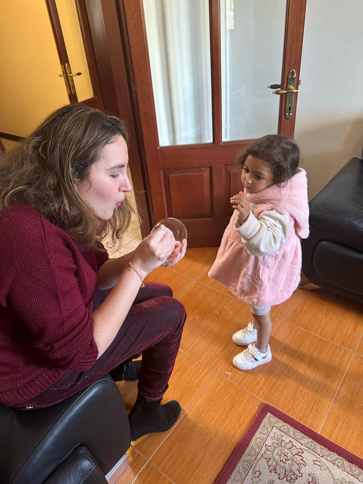 Zahwa Arafat blows soap bubbles with a young girl from Gaza in Malta